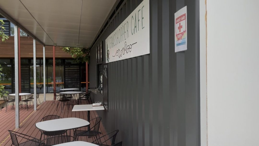 Grasshopper Cafe sign on the container wall beside the covered deck seating