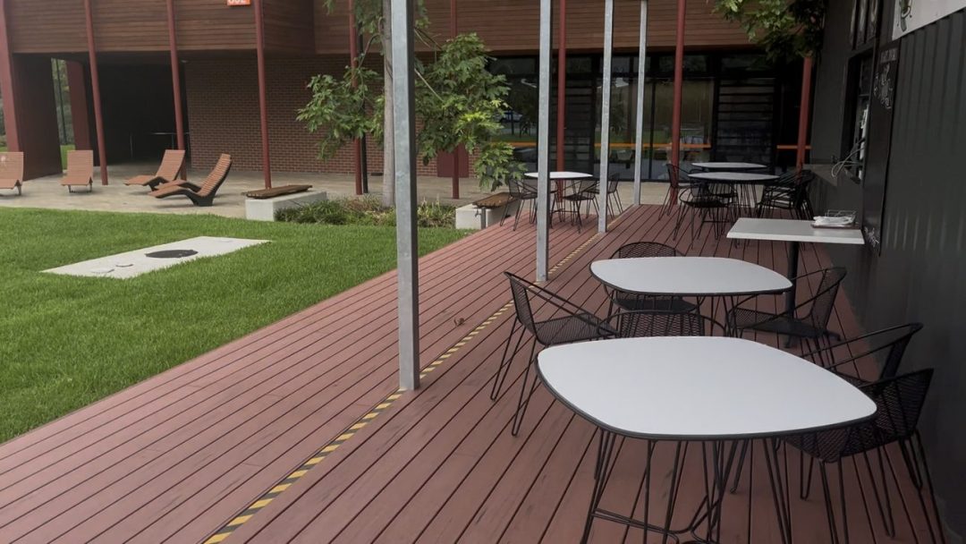 Covered composite deck with outdoor tables and chairs beside the container cafe