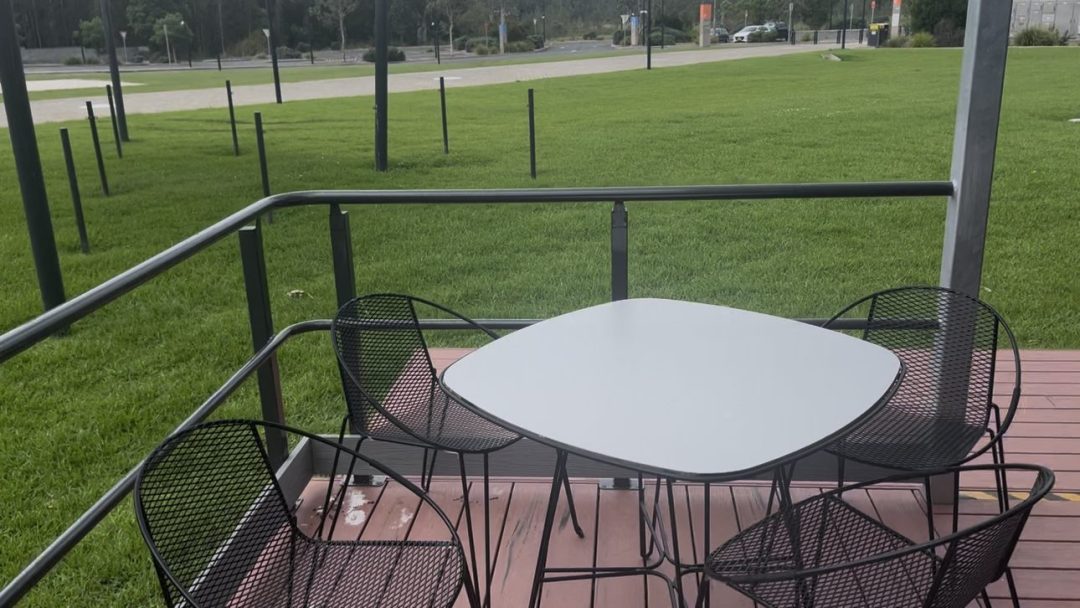 Outdoor table and chairs on the deck overlooking the campus lawn