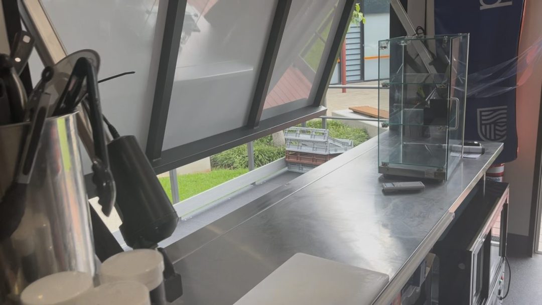 Stainless steel bench and open awning servery window inside the container kitchen