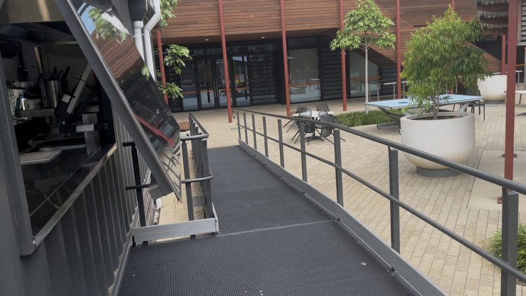 Open servery window beside the accessible ramp, looking across the campus courtyard