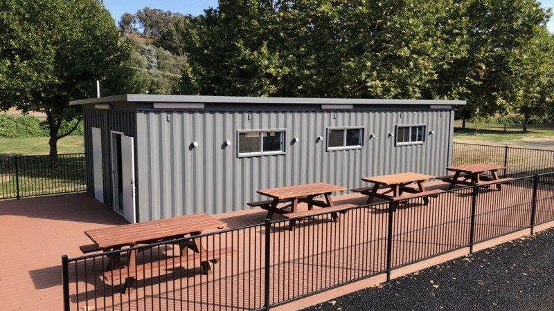 Camp kitchen built from two 40 ft high-cube containers with a fenced deck and picnic tables at Tumbarumba Caravan Park