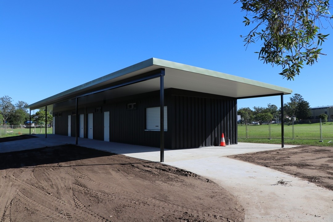 Multi-use amenities block built from shipping containers beside a grassed sports oval