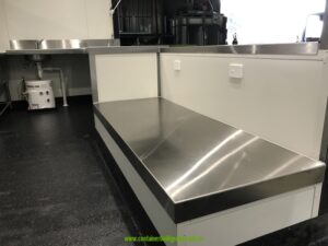 Stainless steel island bench and non-slip coved vinyl floor inside a 20ft commercial kitchen container