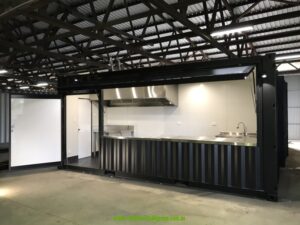 20ft commercial kitchen container in our South Lismore factory with the servery panel open, showing stainless steel benches and range hood