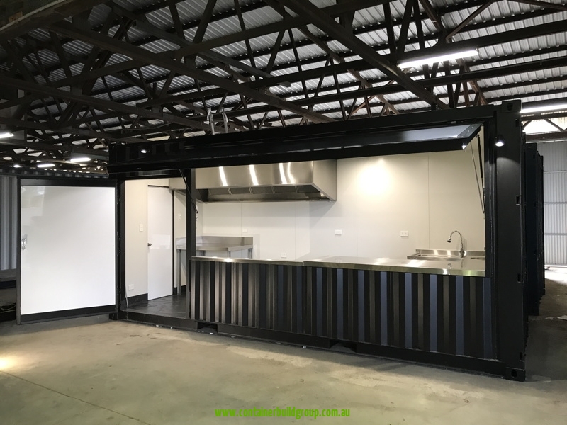 20ft commercial kitchen container in our South Lismore factory with the servery panel open, showing stainless steel benches and range hood